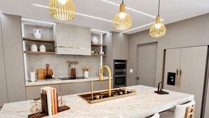 A modern kitchen with a marble countertop, wooden chairs, pendant lights, and built-in appliances. - Luxury Canal Villa, Headed Pool, Game Room, Sandy Beach Yard & Fire Pit (Cape Coral)
