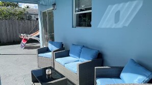 Un patio cubierto con muebles de mimbre y cojines azules.