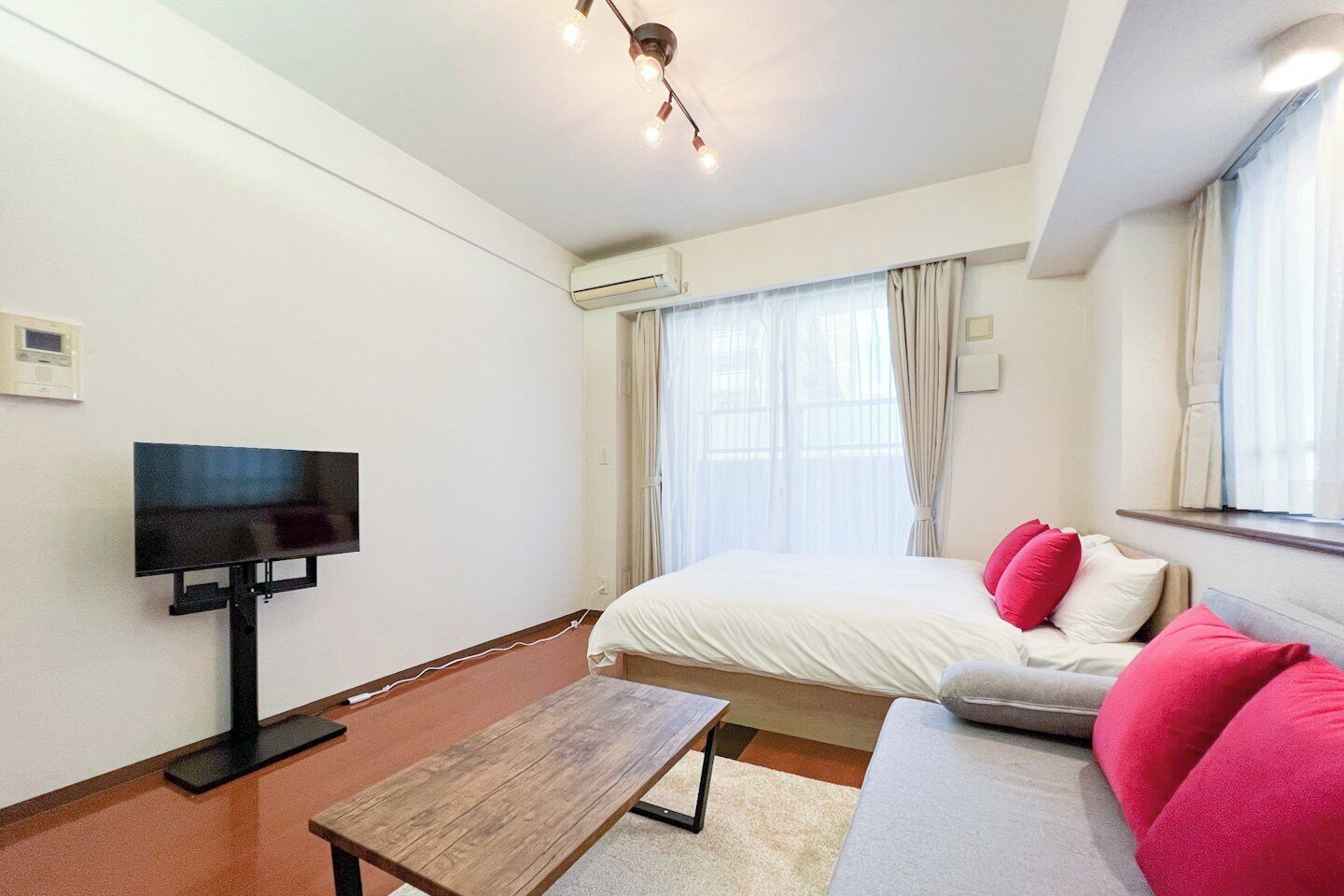 A hotel room with a bed, a sofa, a TV, and a wooden table.