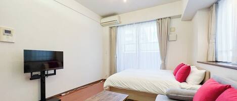 A hotel room with a bed, a sofa, a TV, and a wooden table.
