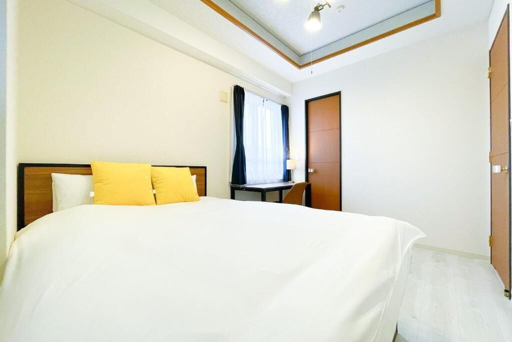 A hotel room with a bed, a desk, a chair, and a wardrobe.