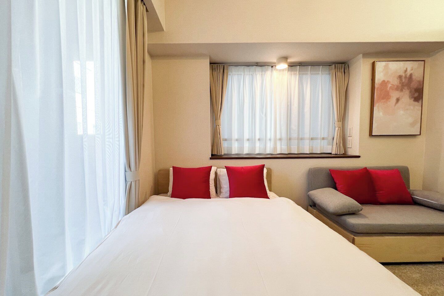 A hotel room with a large bed, a sofa, and a window with curtains.
