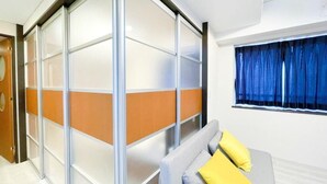 A hotel room with a sliding glass partition, a bed with pillows, a window with curtains, and a wooden door. - CITYSPIRE Sakurakawa II (Osaka)