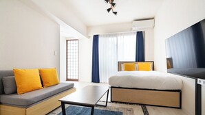 A modern hotel room with a sofa, a bed, a TV, and a window with curtains. - CITYSPIRE Sakurakawa II (Osaka)