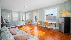 A bedroom with a bed, a sofa, a dining table with chairs, a refrigerator, and a window with blinds. - 9BR Sleeps 19 - 1 Block to Beach - Ocean Views! (Ventnor City)