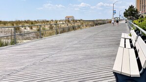 A wooden boardwalk with benches, a railing, and a view of the beach and dunes. - 9BR Sleeps 19 - 1 Block to Beach - Ocean Views! (Ventnor City)