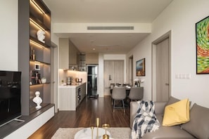 A modern living room with a flat-screen TV, a sofa, and a dining area with chairs. - TROY HOUSE - MASTERI WEST HEIGHTS (Hanoi)