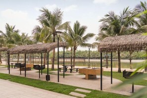 Zona turística con construcciones de techo de paja, asientos exteriores y palmeras.