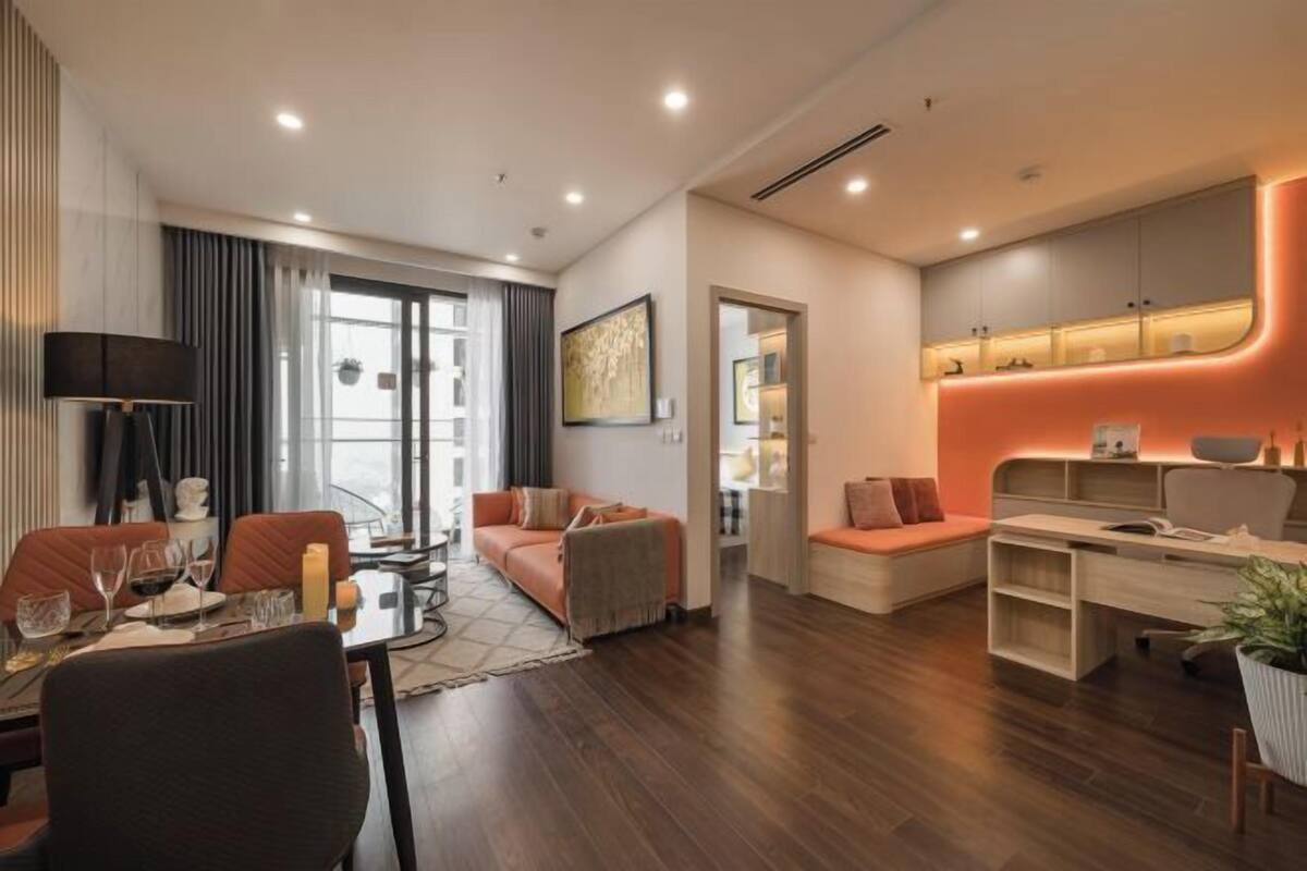 A modern living room with a dining area, a sofa set, a desk, and a kitchen area with a built-in oven.