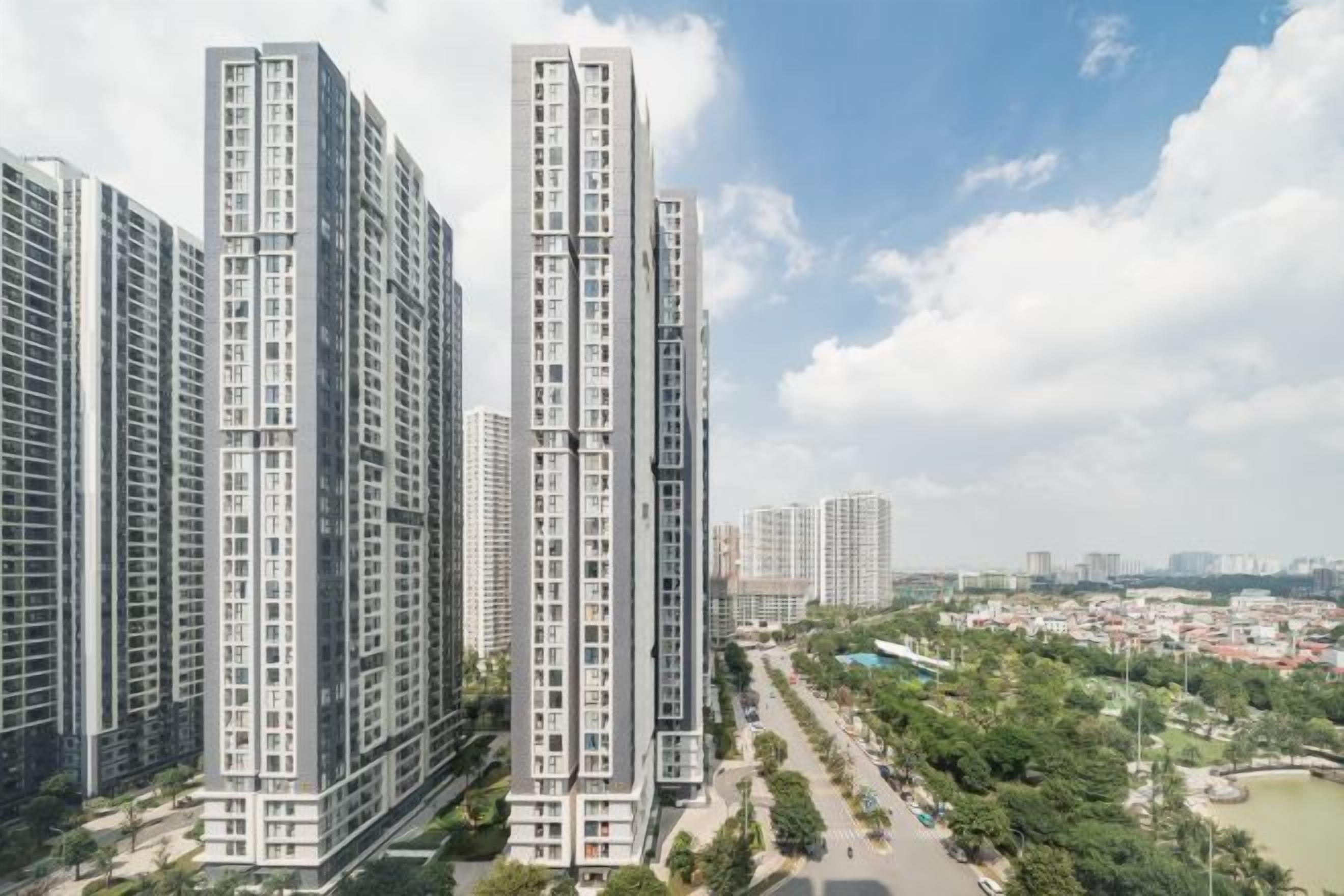 Un ensemble immobilier résidentiel de grande hauteur, composé de plusieurs étages, entouré de verdure et surplombant un ciel dégagé.