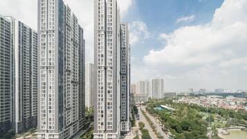 Een hoog appartementencomplex met meerdere verdiepingen, omgeven door groen en een heldere lucht.