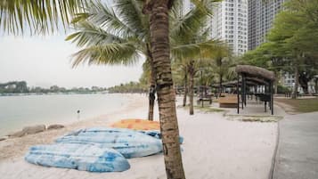 Een strand met palmbomen, een rieten constructie en een kalme zee.