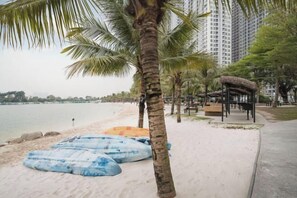 A beach with palm trees, a thatched structure, and a calm sea. - TROY HOUSE - MASTERI WEST HEIGHTS (Hanoi)