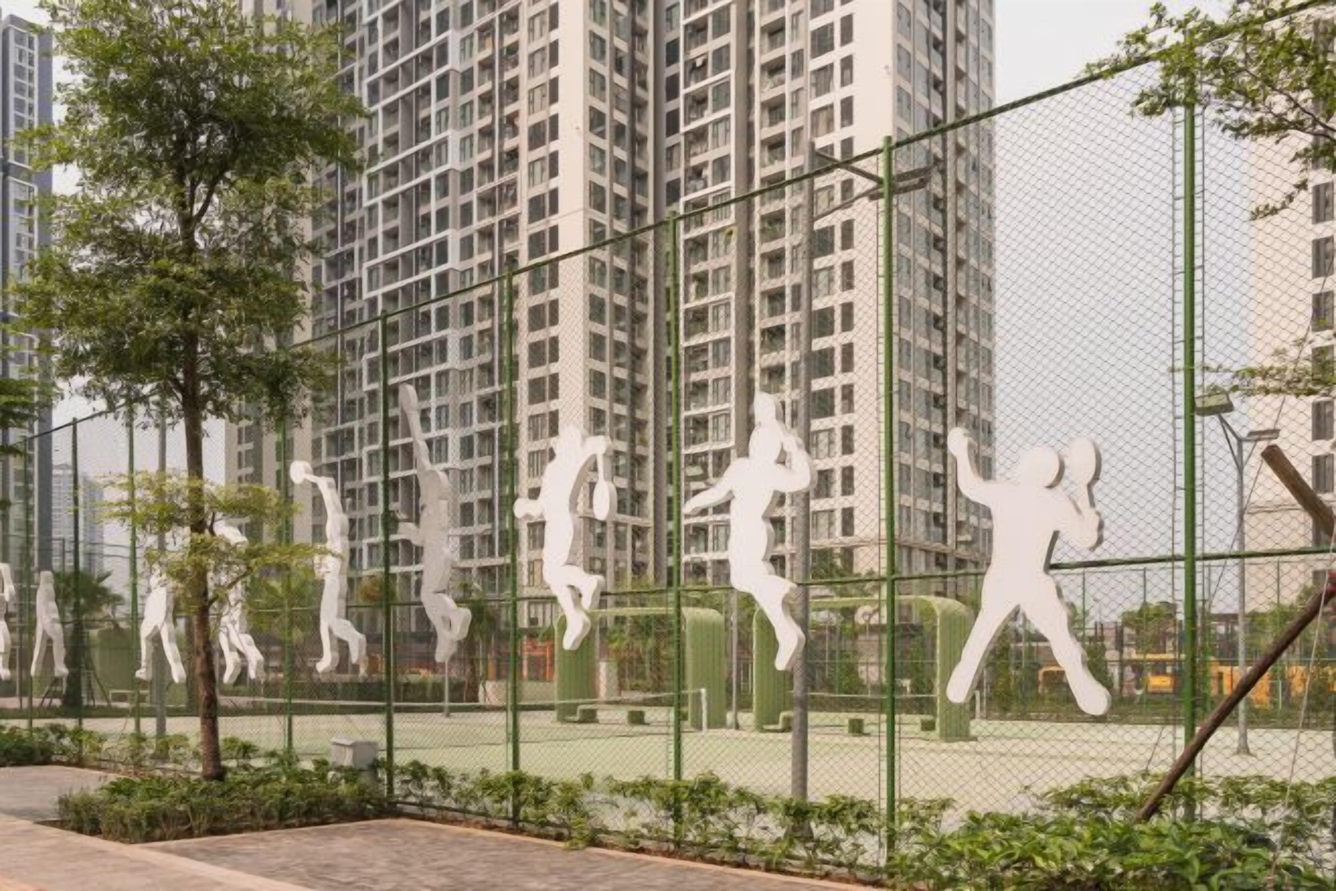 A fenced tennis court with a row of white human figures.