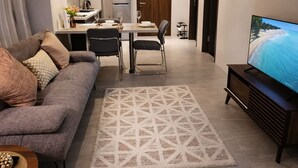 Uma sala de estar moderna com sofá, mesa de jantar, televisão e área de cozinha.