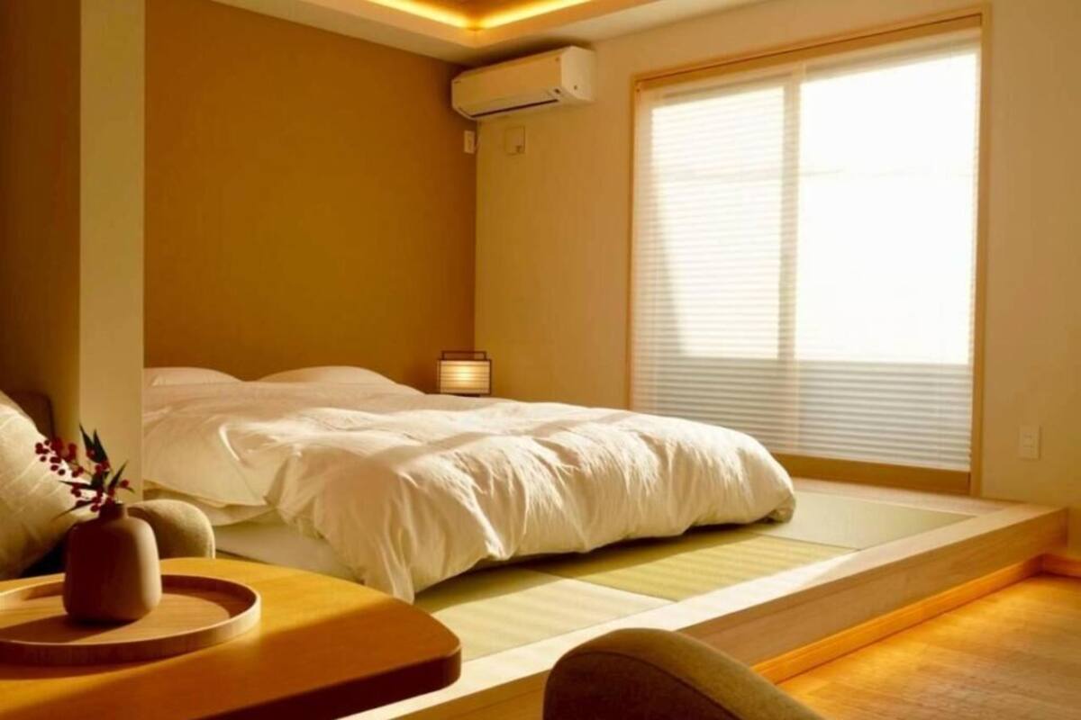 A bedroom with a bed, bedside table, lamp, and window.