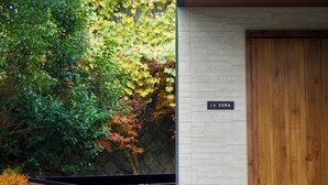 A building entrance with a wooden door, a stone wall, and a sign reading '1F SORA'. - koyado Nagomi (Kobe)