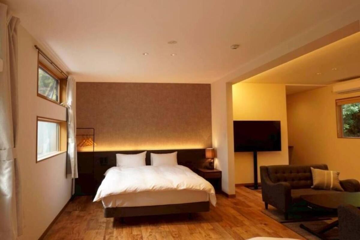 A hotel room with a bed, a TV, a sofa, and a small table.