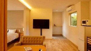 A hotel room with a bed, a sofa, a TV, a microwave, and a small kitchen area. - koyado Nagomi (Kobe)