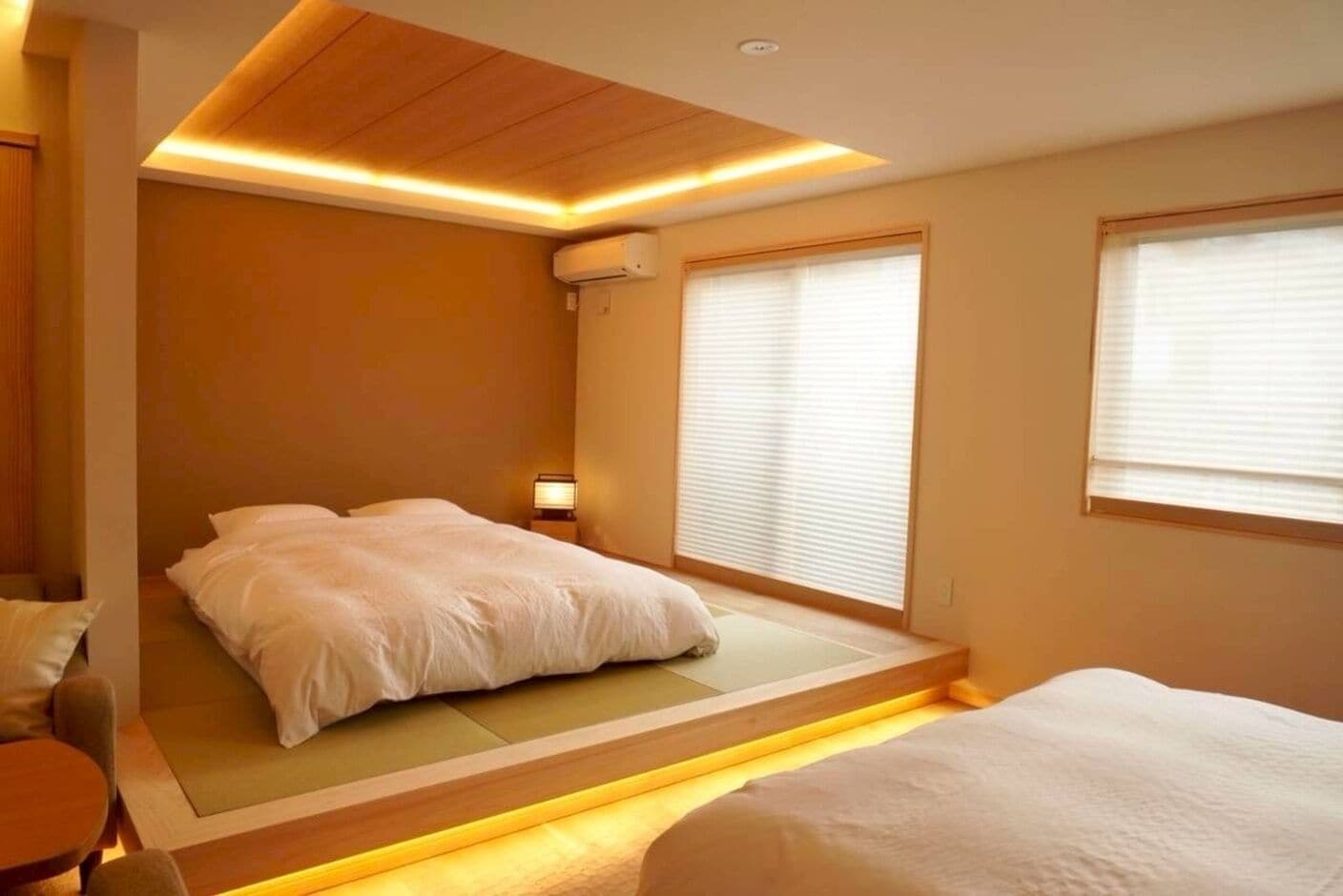 A bedroom with a bed, bedside table, and a window with blinds.