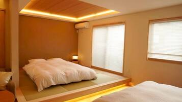 A bedroom with a bed, bedside table, and a window with blinds.