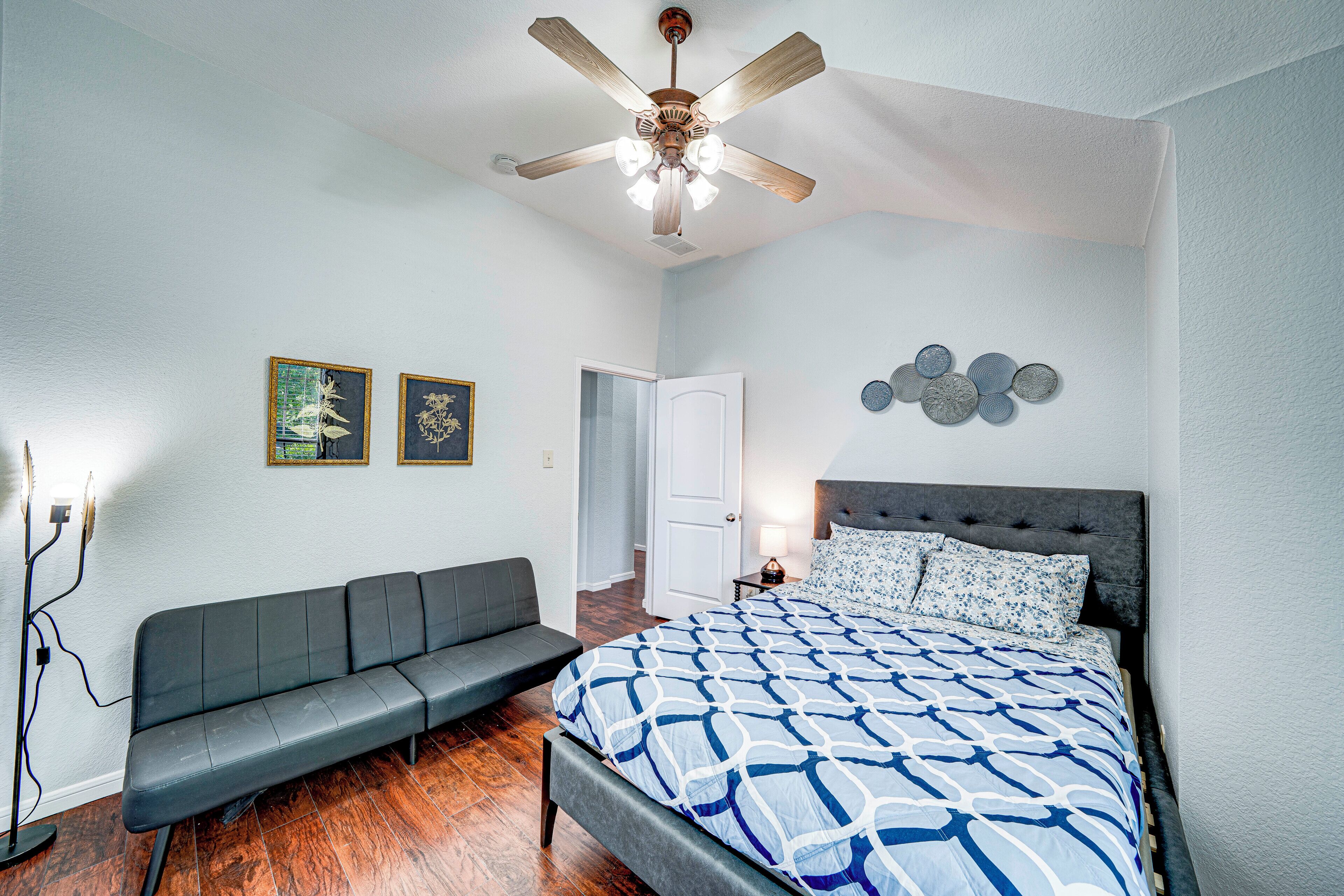 Une chambre à coucher comprenant un lit, un banc, un ventilateur de plafond et des éléments de décoration murale.