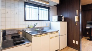 Una cocina compacta con un lavabo, estufa, microondas y una ventana con persianas.
