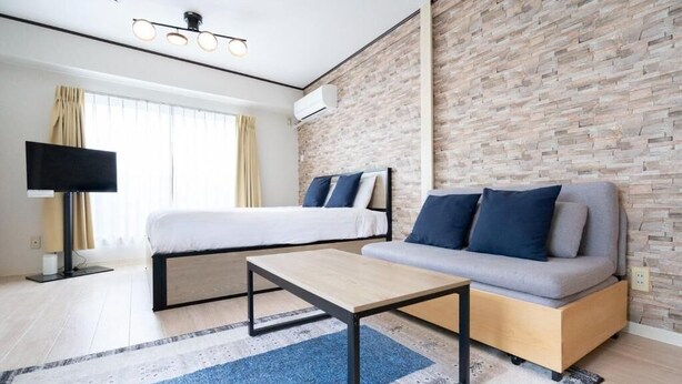 Una habitación de hotel moderna con cama, sofá y televisor de pantalla plana.