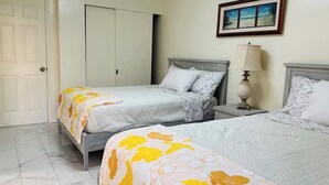 Un dormitorio con dos camas, una puerta, un armario y un cuadro en la pared.
