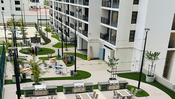 Un patio con mobiliario exterior, una zona de parrillada central y un jardín ajardinado.