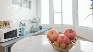 A kitchen with a microwave, a sink, a countertop, and a bowl of apples. - Family Hub at Pratunum (Bangkok)