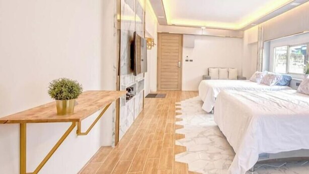 A modern bedroom with a bed, bedside tables, a TV, and a small plant. - Family Hub at Pratunum (Bangkok)