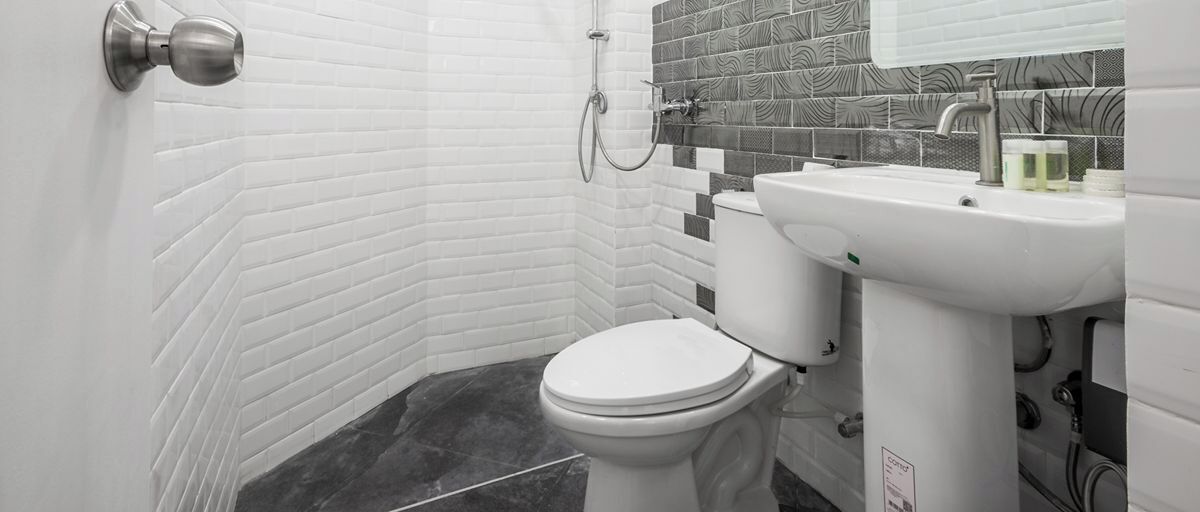 A bathroom with a white toilet, a sink, and a shower.