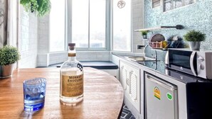 A kitchen with a wooden table, a bottle of Monkey Shoulder whiskey, a glass, and a potted plant. - Family Hub at Pratunum (Bangkok)