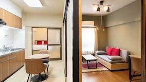 Een knus woongedeelte met een kitchenette, een eethoek, een bank en een kleine tafel.