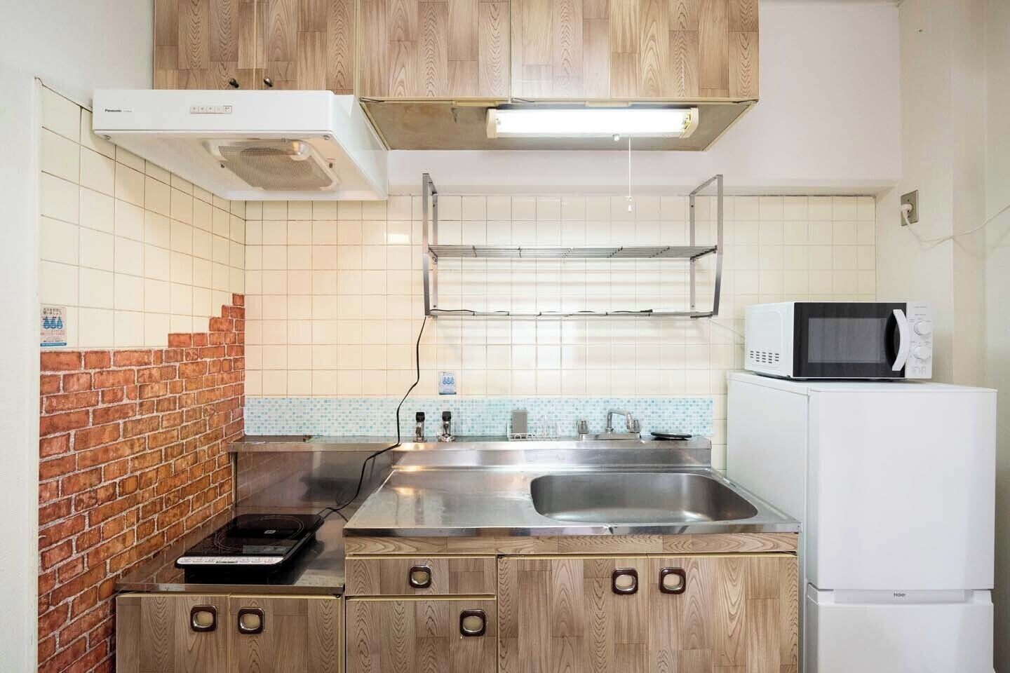 Una cocina con microondas, estufa, lavabo y armarios de madera.