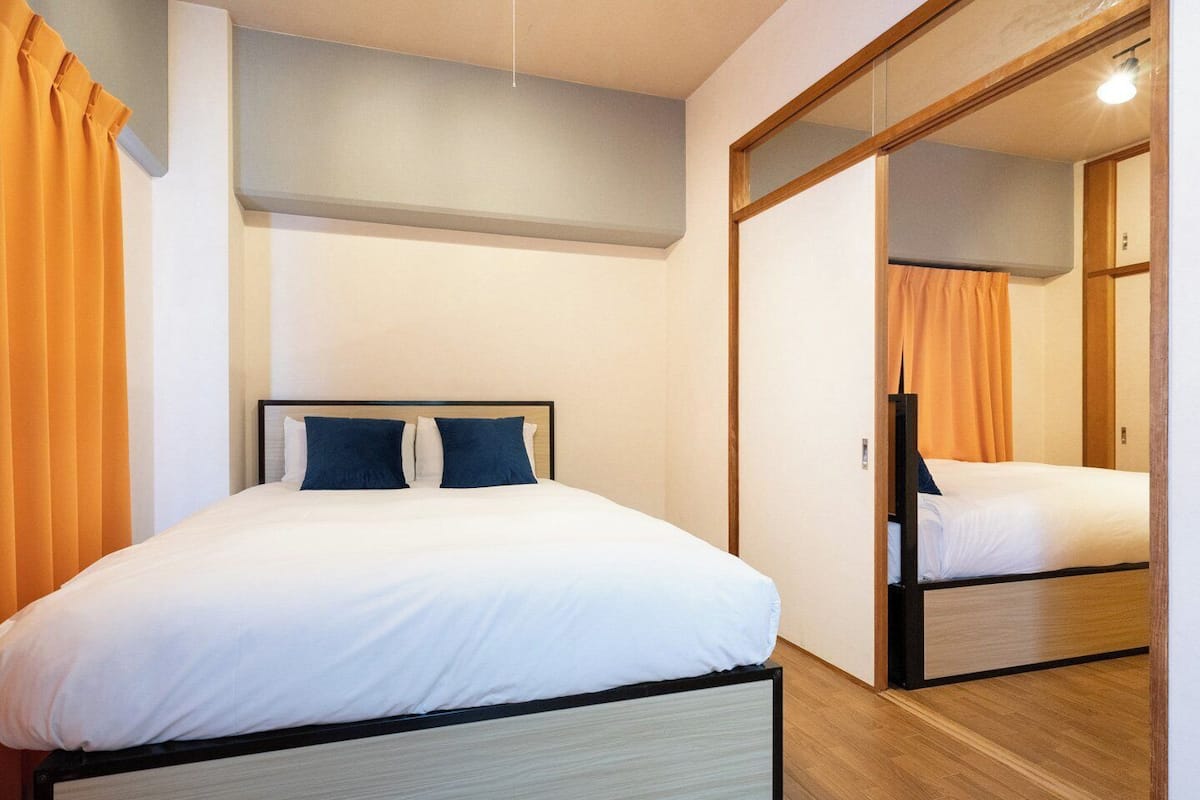 A hotel room with a bed, a mirror, and a wardrobe.