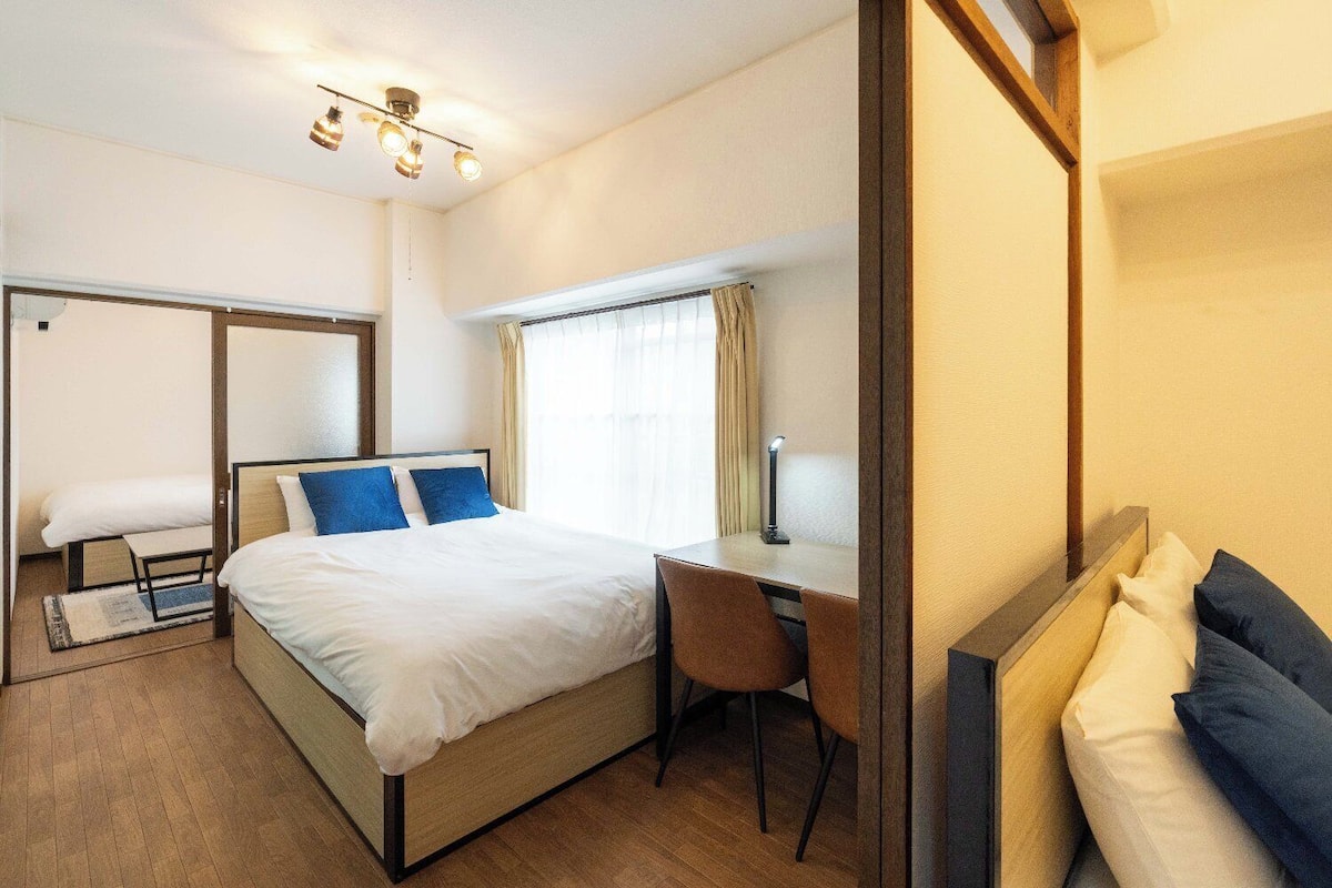 A hotel room with a bed, a desk, a chair, and a window with curtains.
