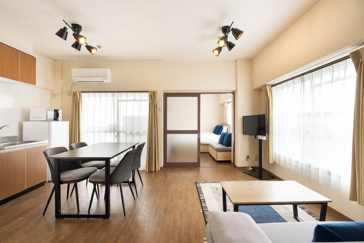 A hotel room with a dining area, a sofa, a TV, and a bed.