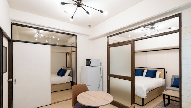 Een kleine hotelkamer met een bed, een tafeltje en een stoel.