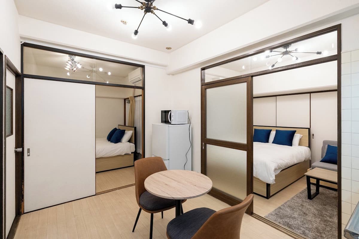A compact hotel room with a bed, a small table, and a chair.