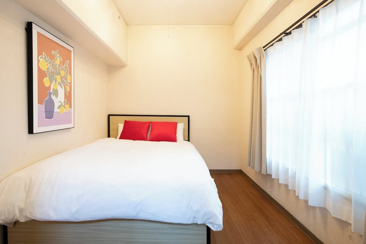 A hotel room with a bed, a framed picture on the wall, and a window with curtains.