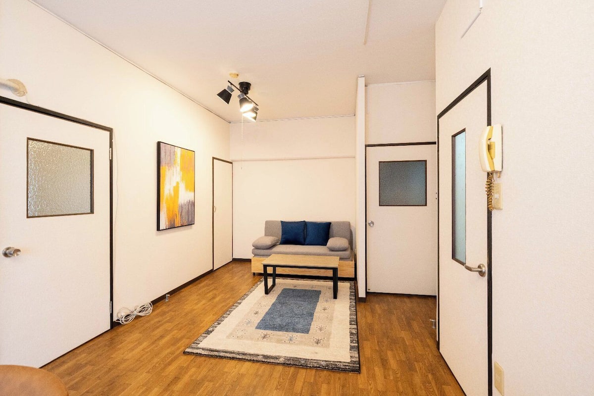A hallway with a sofa, a rug, and framed pictures on the walls.