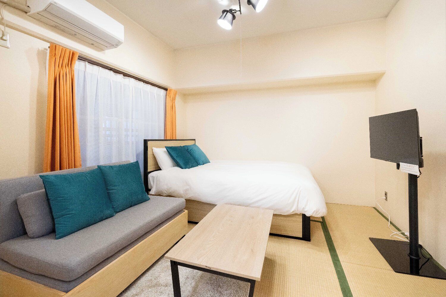 Une chambre d’hôtel équipée d’un lit, d’un canapé, d’une petite table, d’une télévision et d’un appareil de climatisation.