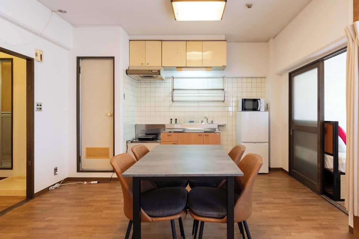 A compact kitchen with a dining table, chairs, a microwave, and a refrigerator.