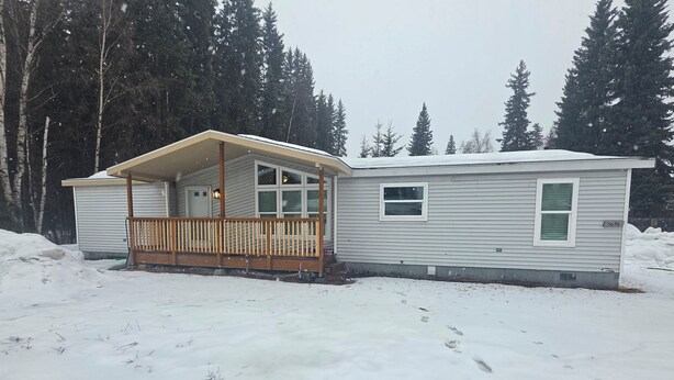 Une maison mobile de plain-pied, dotée d’un porche, d’un petit garage attenant et du numéro « 3696 » peint sur le côté.