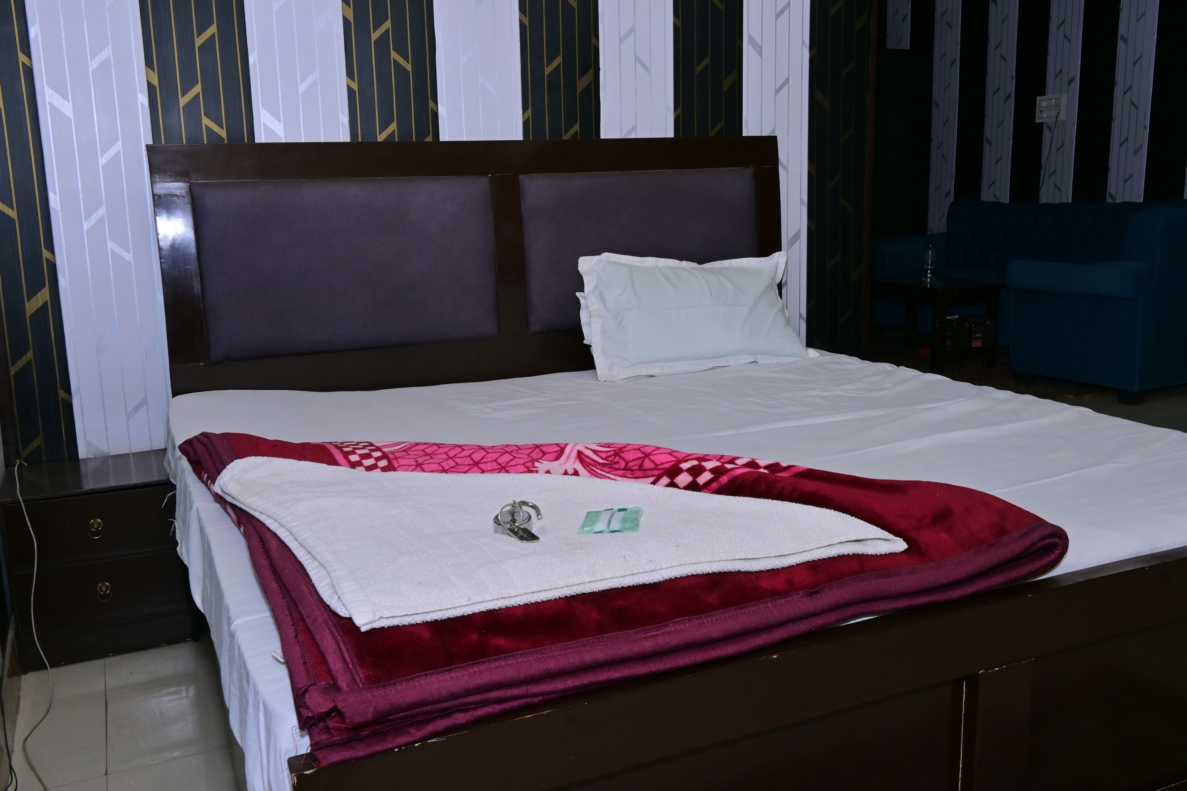 A neatly made bed with a red blanket, a white pillow, and a headboard.