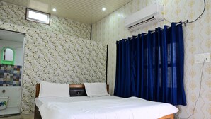 A bedroom with a bed, a mirror, an air conditioner, and patterned wallpaper. - Hotel Awadh Vilas (Ayodhya)