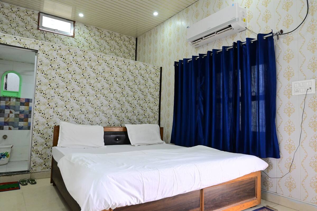 Un dormitorio con cama, espejo, aire acondicionado y papel tapiz estampado.