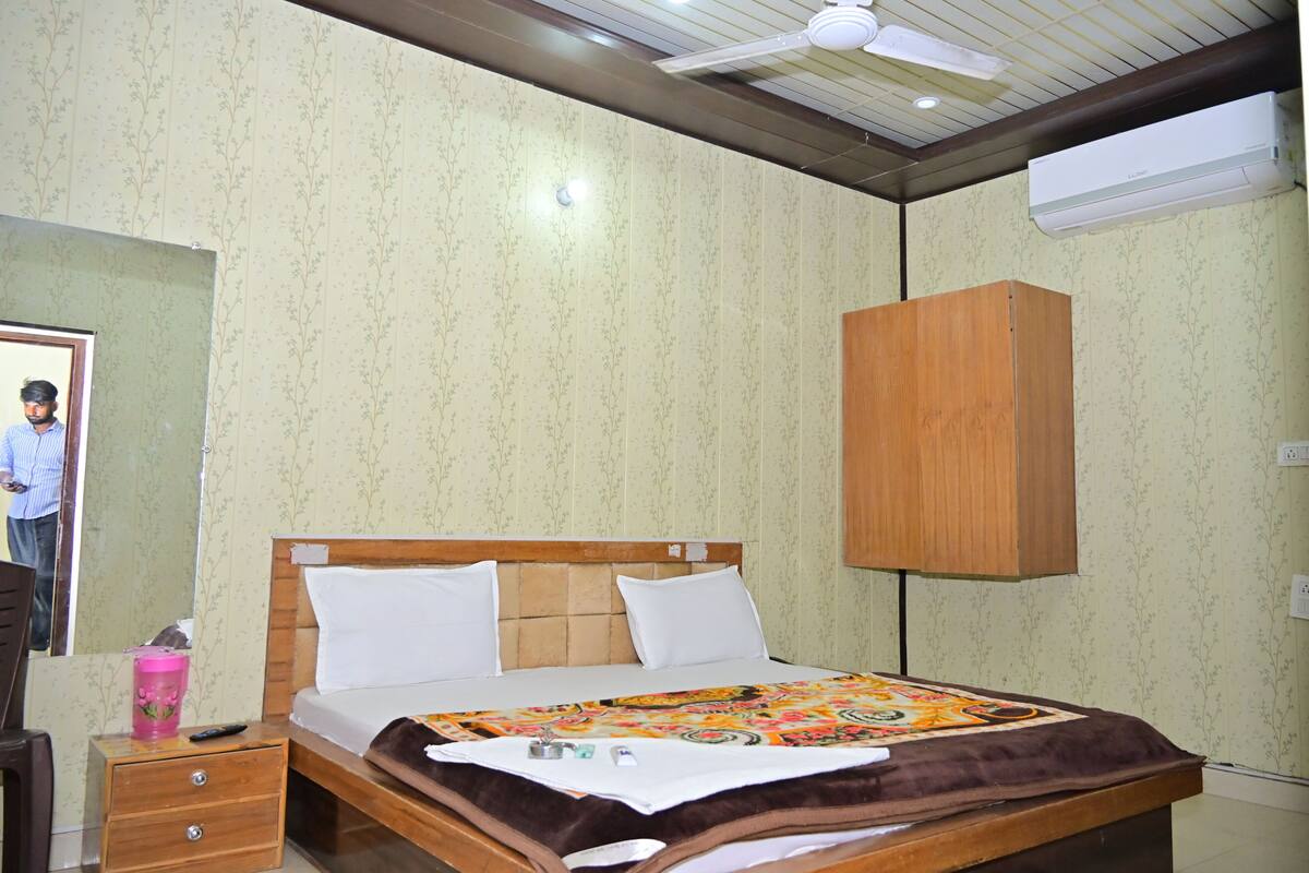 Un dormitorio con cama, cabecero de madera, mesita de noche, espejo y armario.